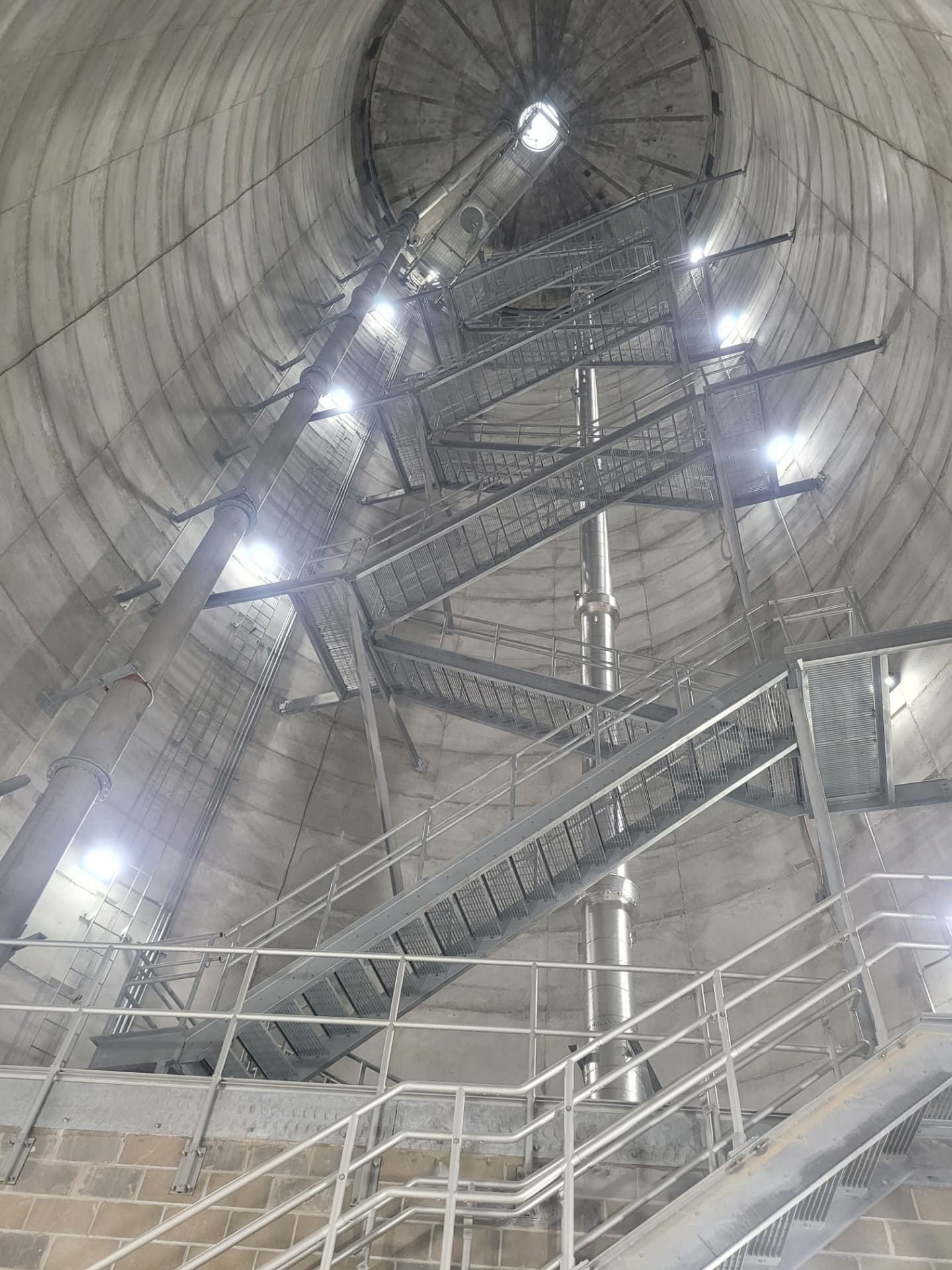 Interior of a concrete water storage tank with galvanized stair towers, catwalks, riser piping and LED lighting installed by Max Electric