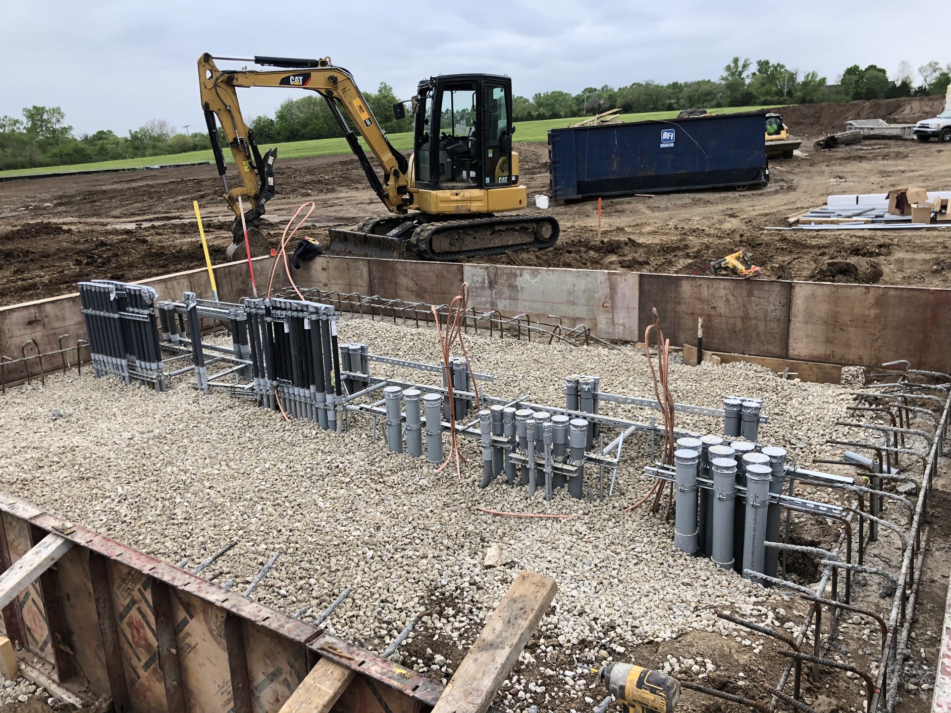 Excavator and under-slab conduit stub-ups at a new industrial construction site