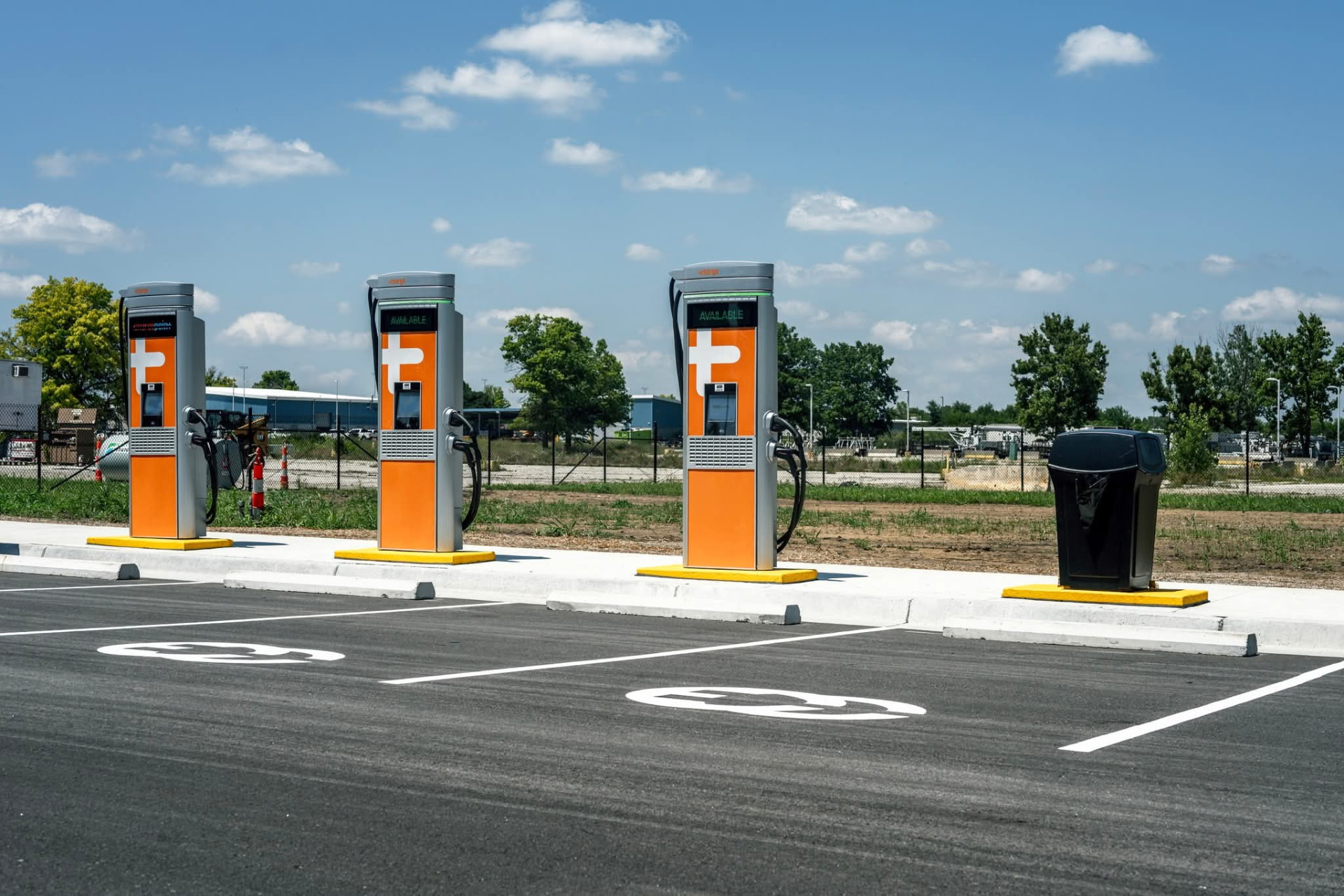 Three orange ChargePoint EV charging stations installed in a commercial parking lot